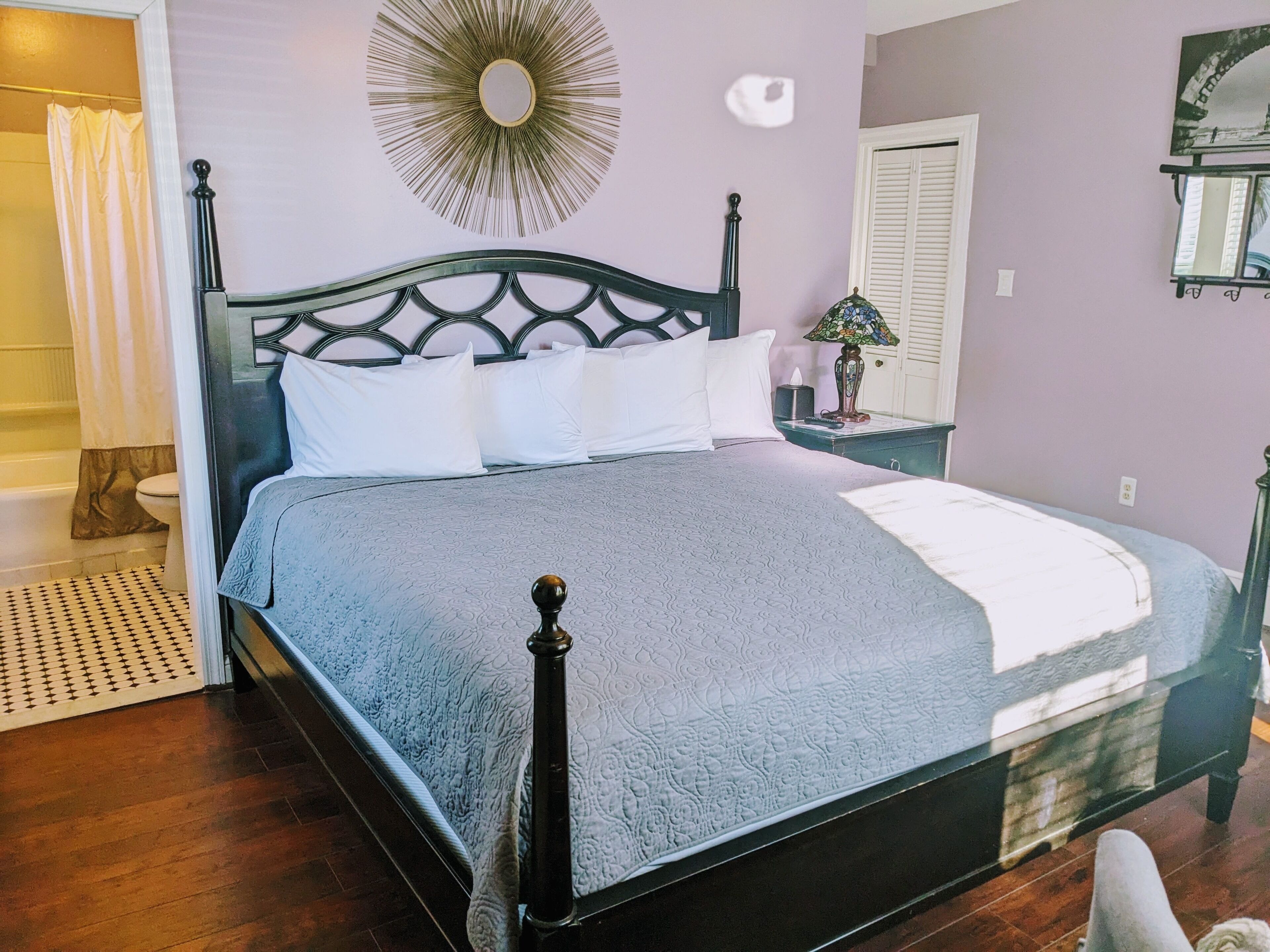 A bedroom with a bed, a nightstand, a lamp, and a wall decoration.