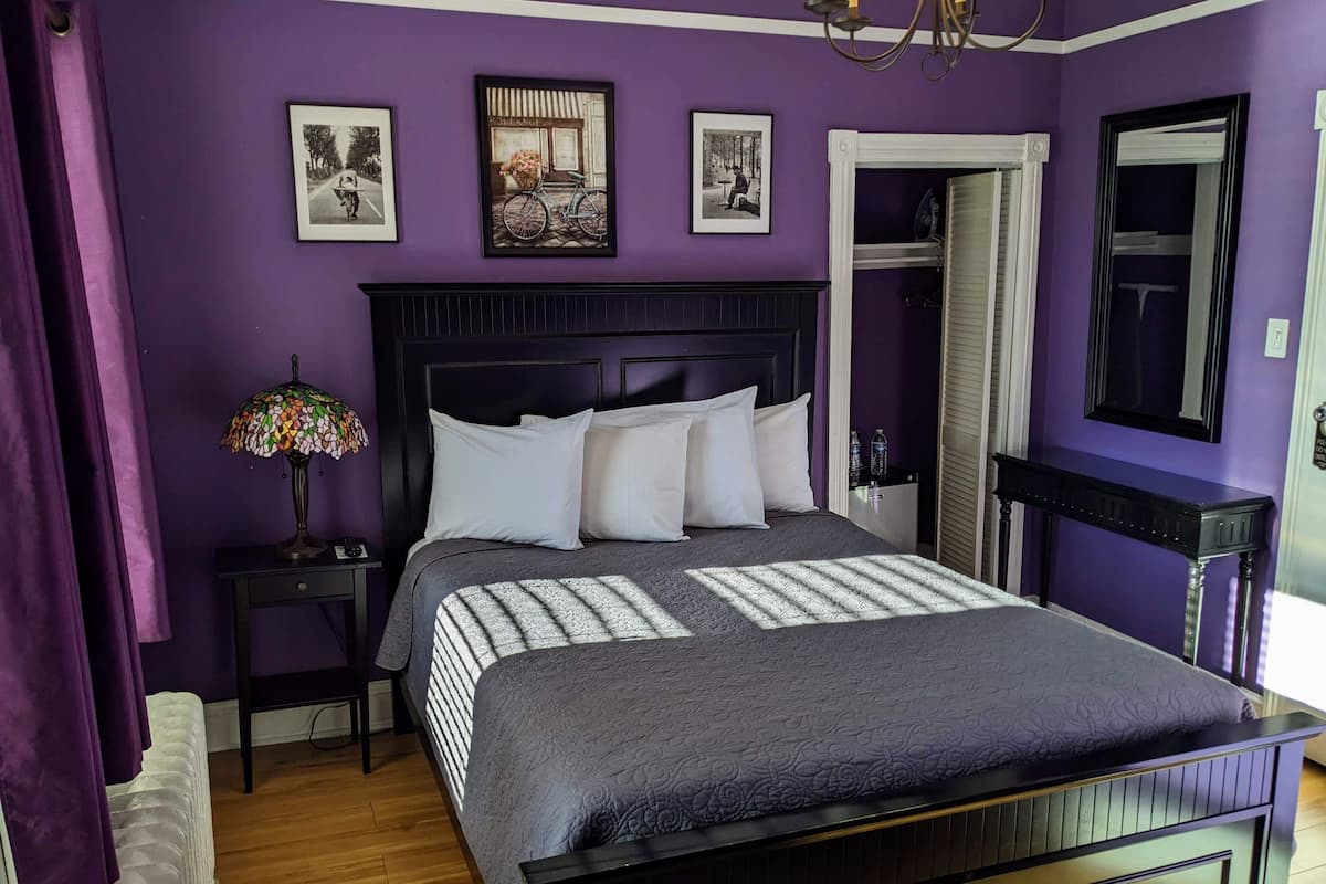 A bedroom with a bed, a nightstand, a lamp, and a mirror.