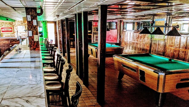 A bar area with a pool table, chairs, and a marble counter.