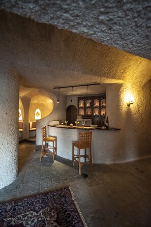 A cozy interior with a bar area, wooden chairs, and a patterned rug. - Uchisar Kaya Hotel - Special Class (Nevsehir)
