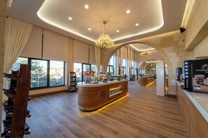 A spacious hotel lobby with a central bar area, large windows, and a wooden floor. - Uchisar Kaya Hotel - Special Class (Nevsehir)