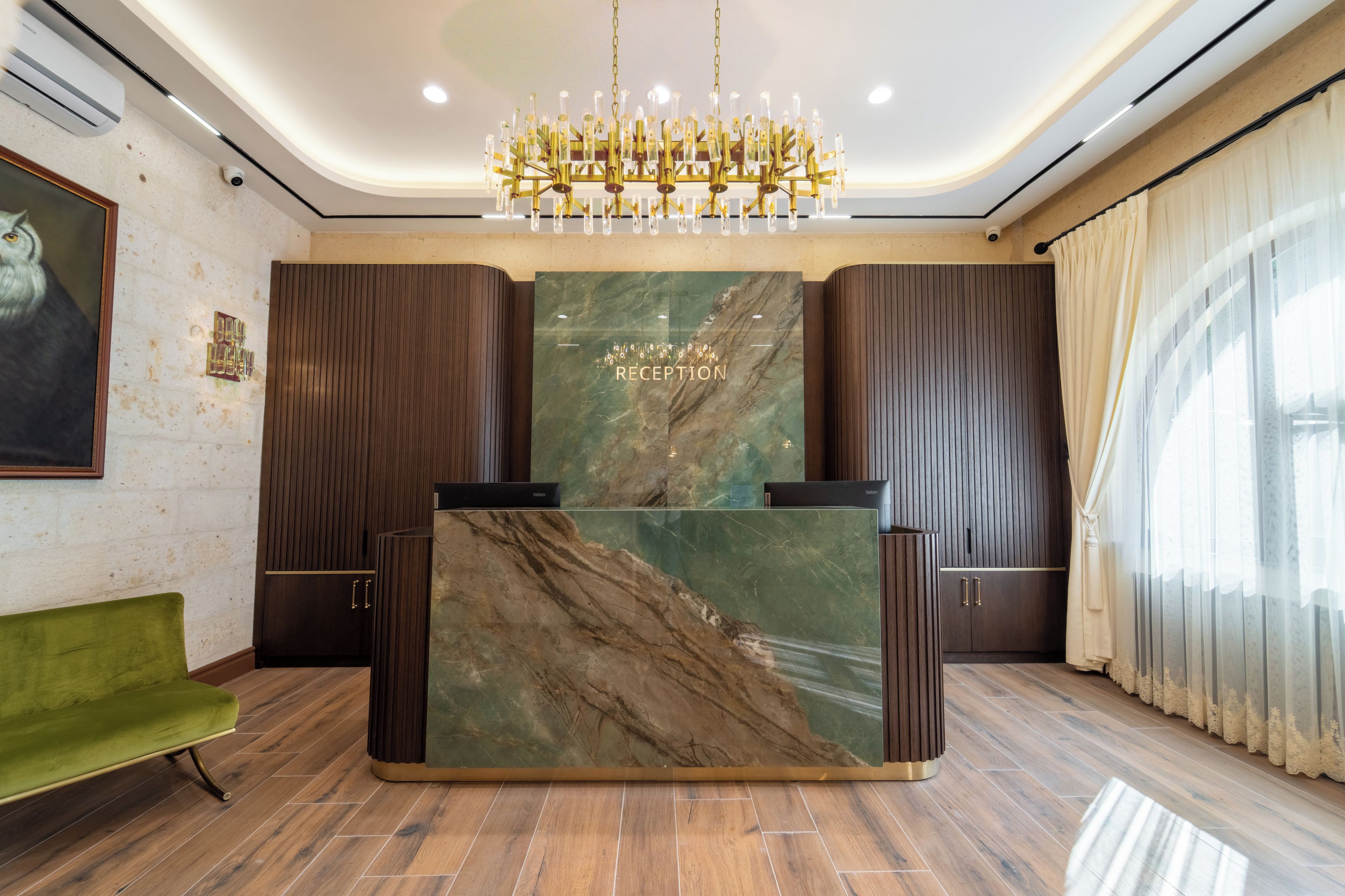 A reception desk with a marble top, flanked by wooden paneling, and a chandelier above.