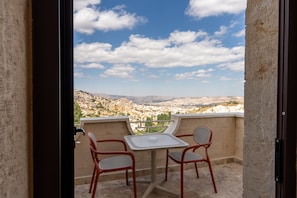 A balcony with a table and two chairs, overlooking a mountainous landscape. - Uchisar Kaya Hotel - Special Class (Nevsehir)