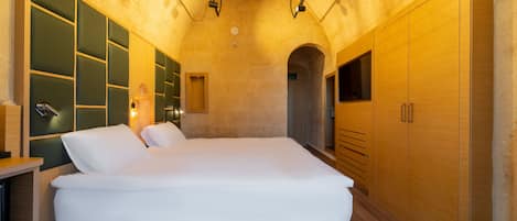 A modern bedroom with a large bed, built-in wooden cabinets, and a stone wall.