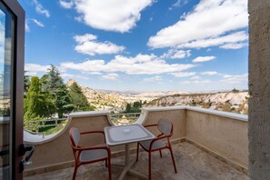 A balcony with a table and chairs overlooking a scenic landscape. - Uchisar Kaya Hotel - Special Class (Nevsehir)