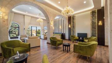 A spacious lobby with high ceilings, arched alcoves, and a grand chandelier.