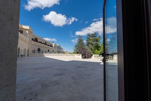 A spacious courtyard with a building featuring arched windows and a red flag on top. - Uchisar Kaya Hotel - Special Class (Nevsehir)