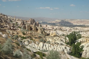 A rugged landscape with a village nestled among rocky formations. - Uchisar Kaya Hotel - Special Class (Nevsehir)