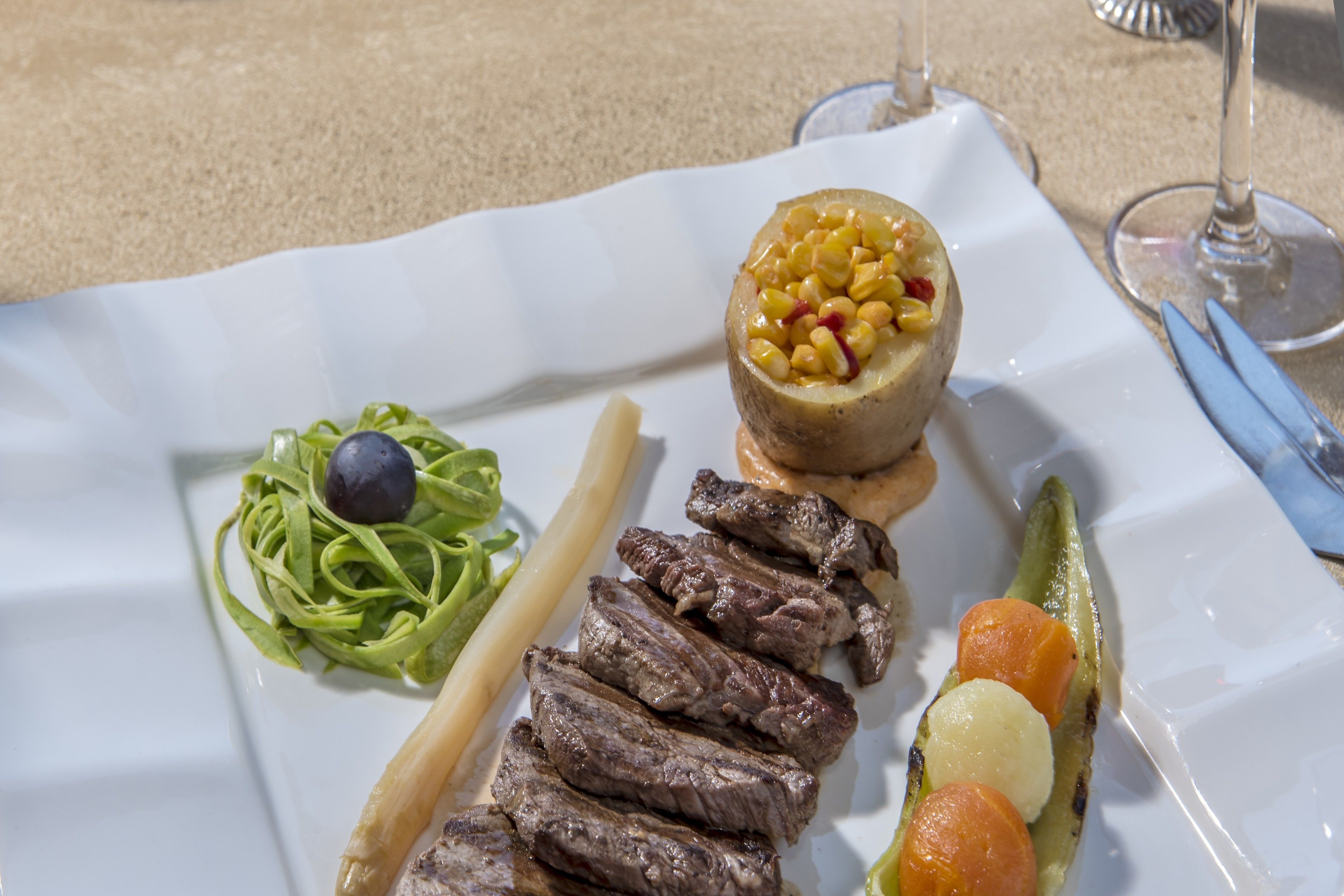 A white plate with a variety of food items including pasta, steak, and vegetables.