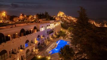 Un hotel con piscina, ventanas de arco y vistas a la montaña.