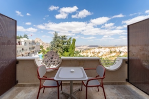 A balcony with a table and chairs, overlooking a mountainous landscape with a clear sky. - Uchisar Kaya Hotel - Special Class (Nevsehir)