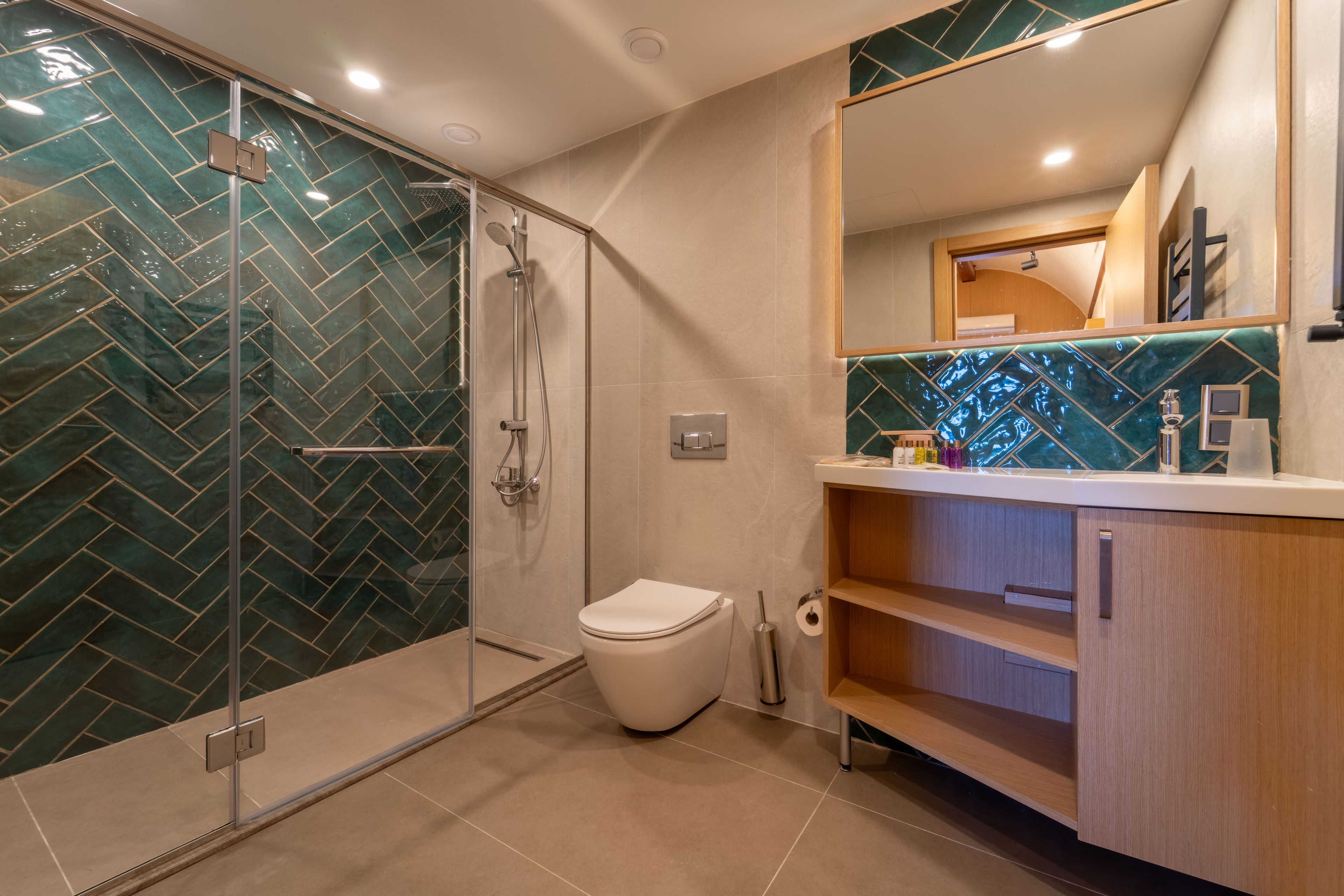 Une salle de bain moderne dotée d’une douche à parois de verre, de toilettes et d’un meuble-lavabo avec un miroir.