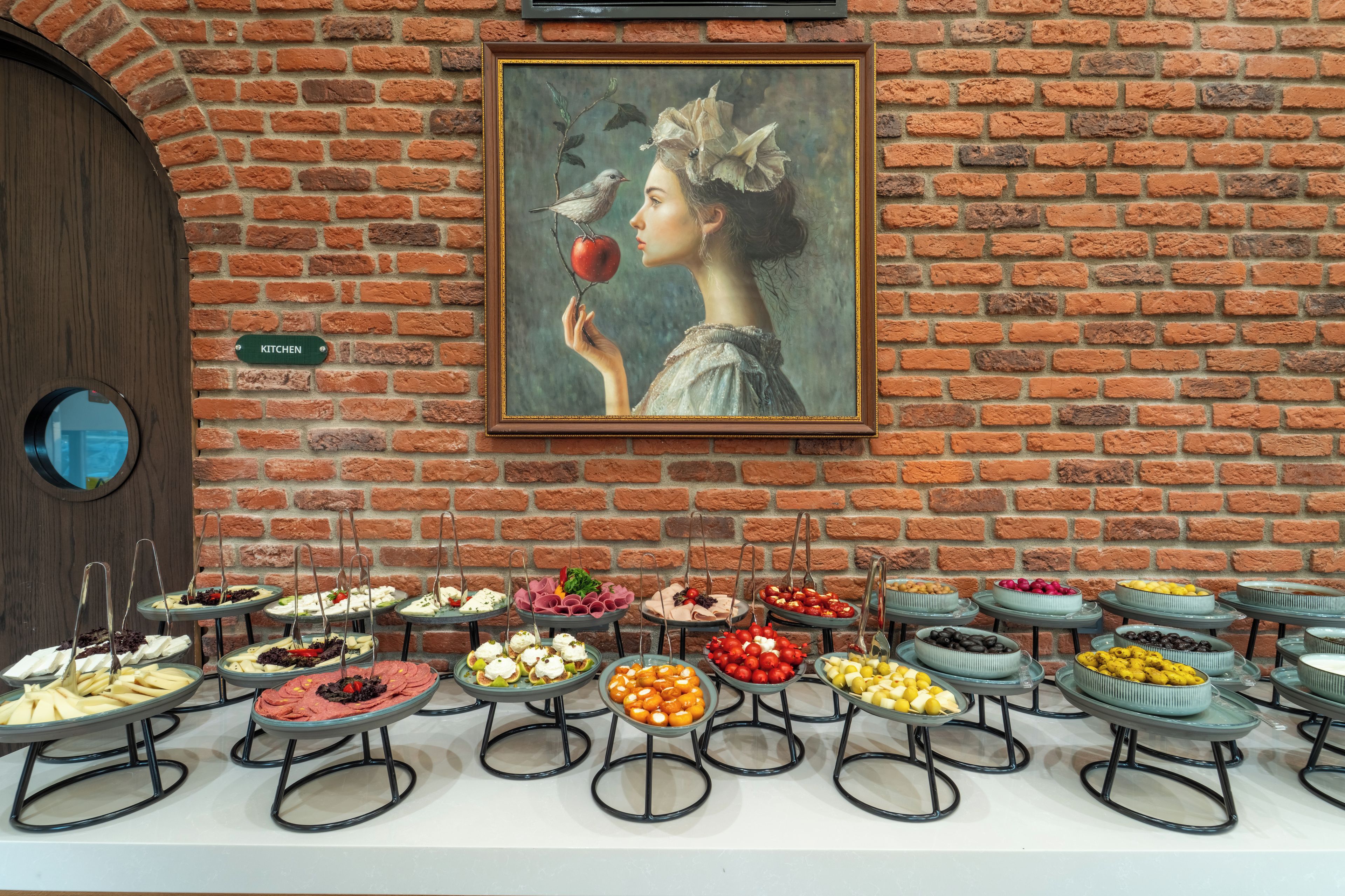 En buffet med forskellige retter, et billede på væggen og et skilt, der viser køkkenområdet.