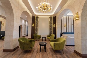 A lobby with a chandelier, green upholstered chairs, a reception desk, and marble accents. - Uchisar Kaya Hotel - Special Class (Nevsehir)