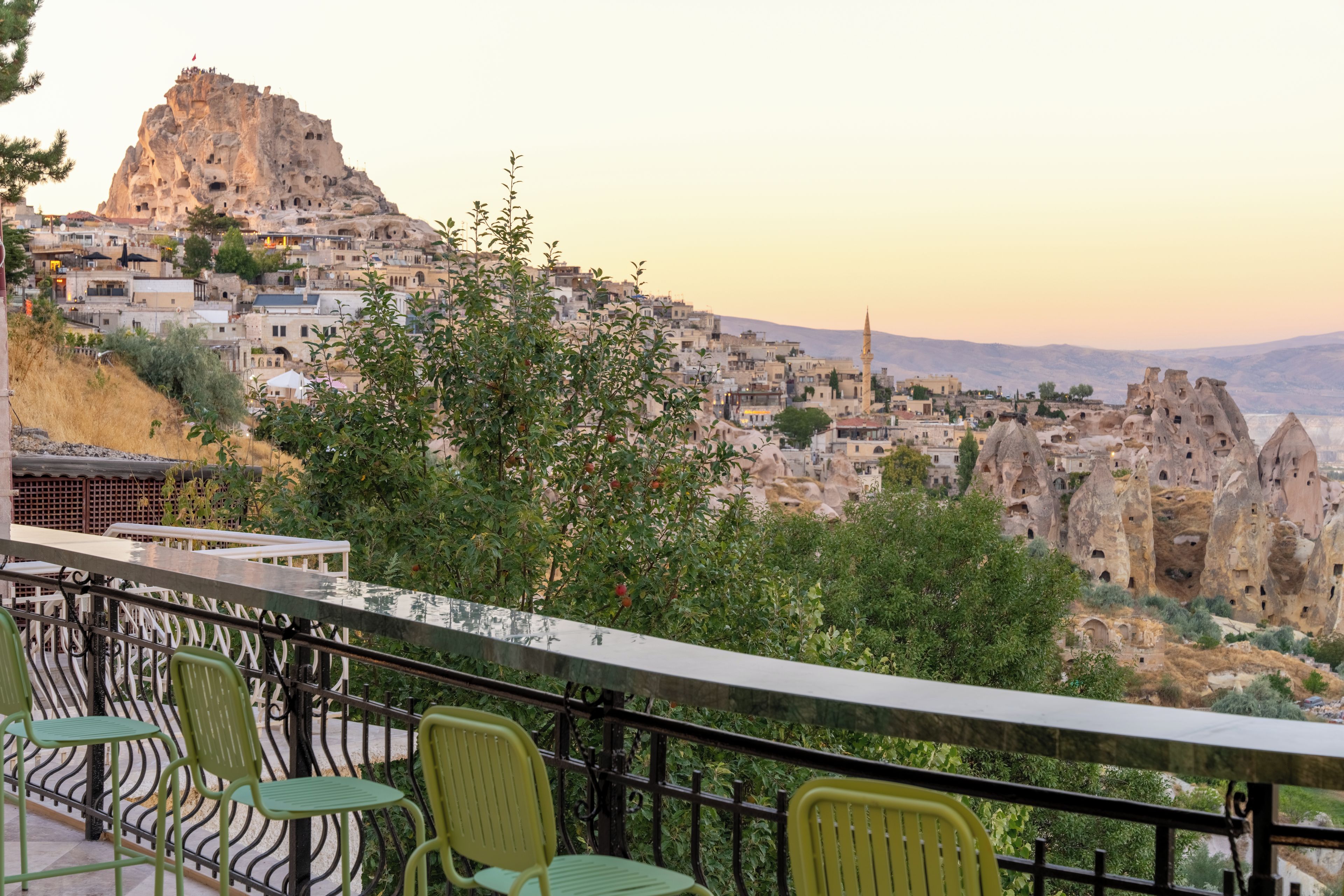 A terrace with chairs overlooking a historic cityscape with unique rock formations and traditional buildings.