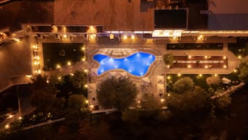 Vue aérienne d’un complexe hôtelier doté d’une piscine centrale, entourée de jardins aménagés et d’espaces de détente en plein air.