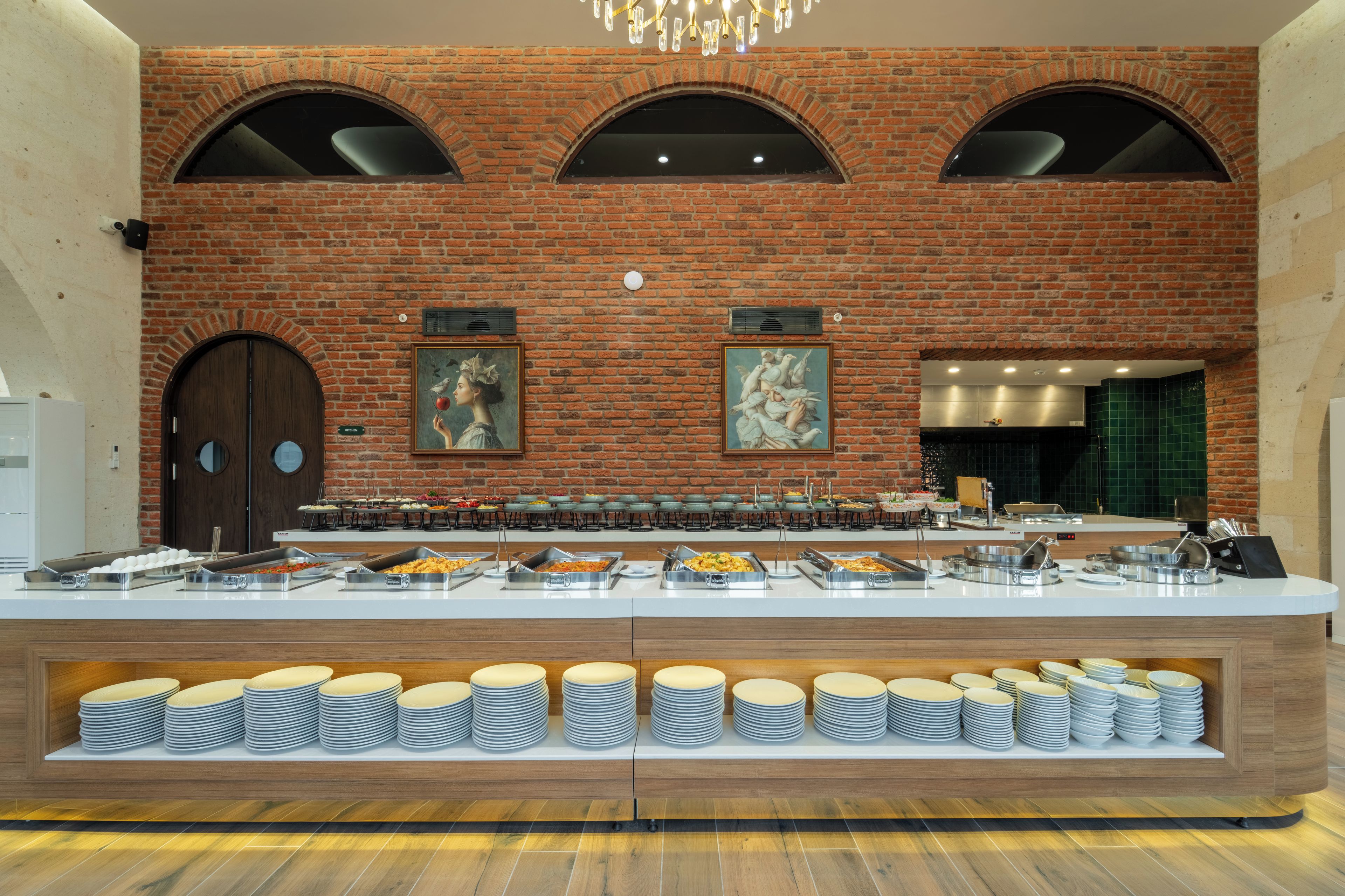 Disposição de buffet com diversas estações de comida e parede de tijolos ao fundo.