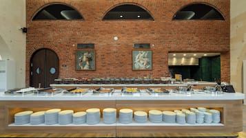 Disposição de buffet com diversas estações de comida e parede de tijolos ao fundo.