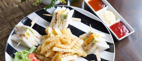 Un plato con sándwiches, papas fritas y ensalada, acompañado de recipientes pequeños de kétchup y mayonesa.
