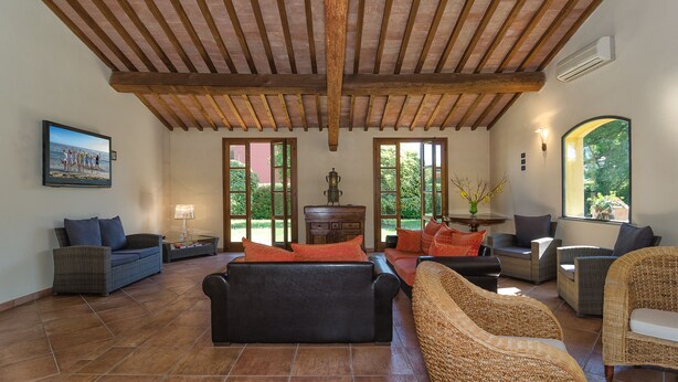 Amplia sala de estar con techo de madera, ventanas grandes y cómodos muebles.