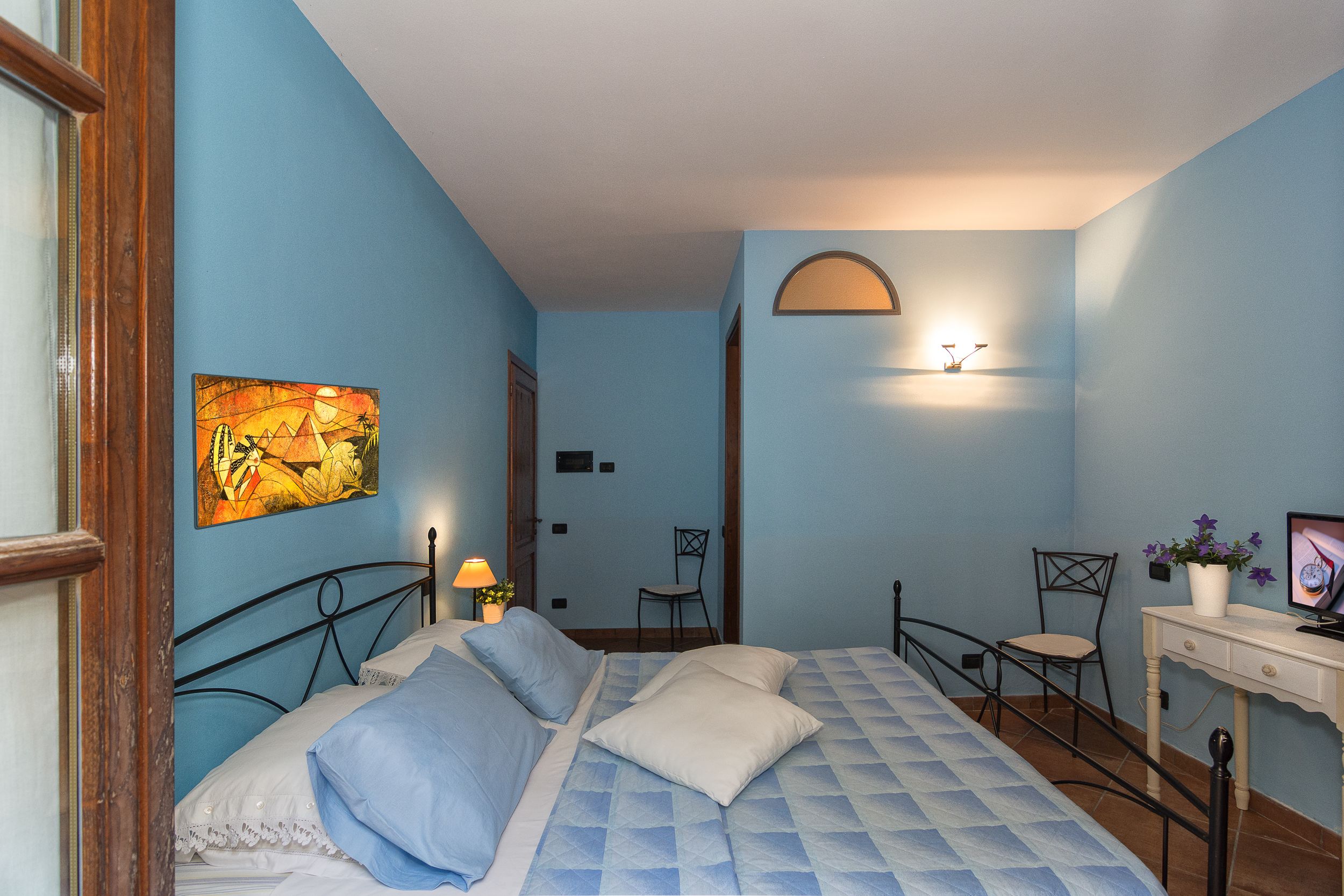 Une chambre à coucher comprenant un lit, un bureau, une chaise et une lampe fixée au mur.