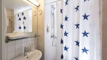 A bathroom with a sink, mirror, and shower.