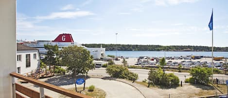 Vista da un balcone su un'area parcheggio, con uno specchio d'acqua, una bandiera e un edificio con una 'G' rossa sul tetto.