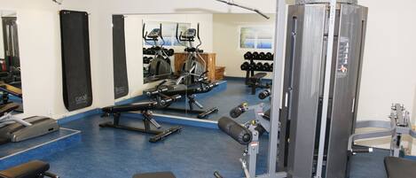 A gym with exercise equipment, a mirror, and a blue floor.