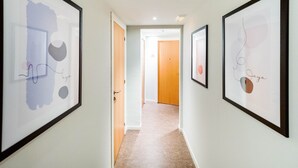 Un pasillo con obras de arte abstracto enmarcadas en las paredes, que conduce a una puerta con el número 205.