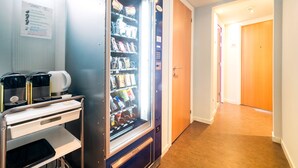 Una habitación de hotel con minibar, cafetera y una puerta que da a otra habitación.