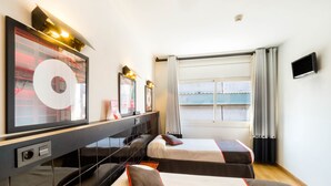 Habitación de hotel con dos camas, un espejo grande, obras de arte y un televisor.