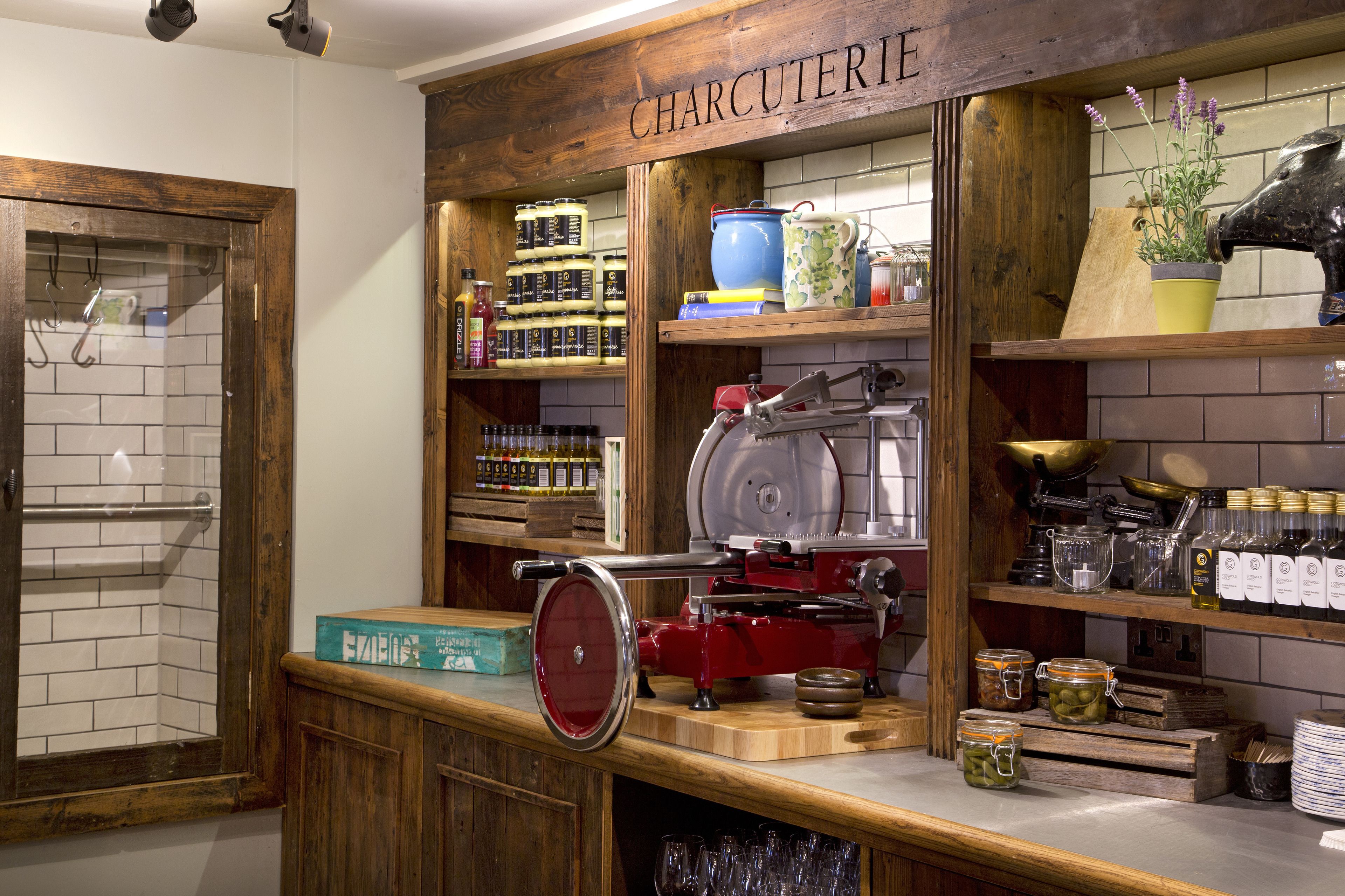 A kitchen area with a wooden countertop, a meat slicer, and various jars of condiments.