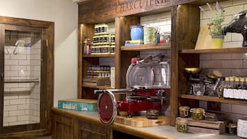 A kitchen area with a wooden countertop, a meat slicer, and various jars of condiments.