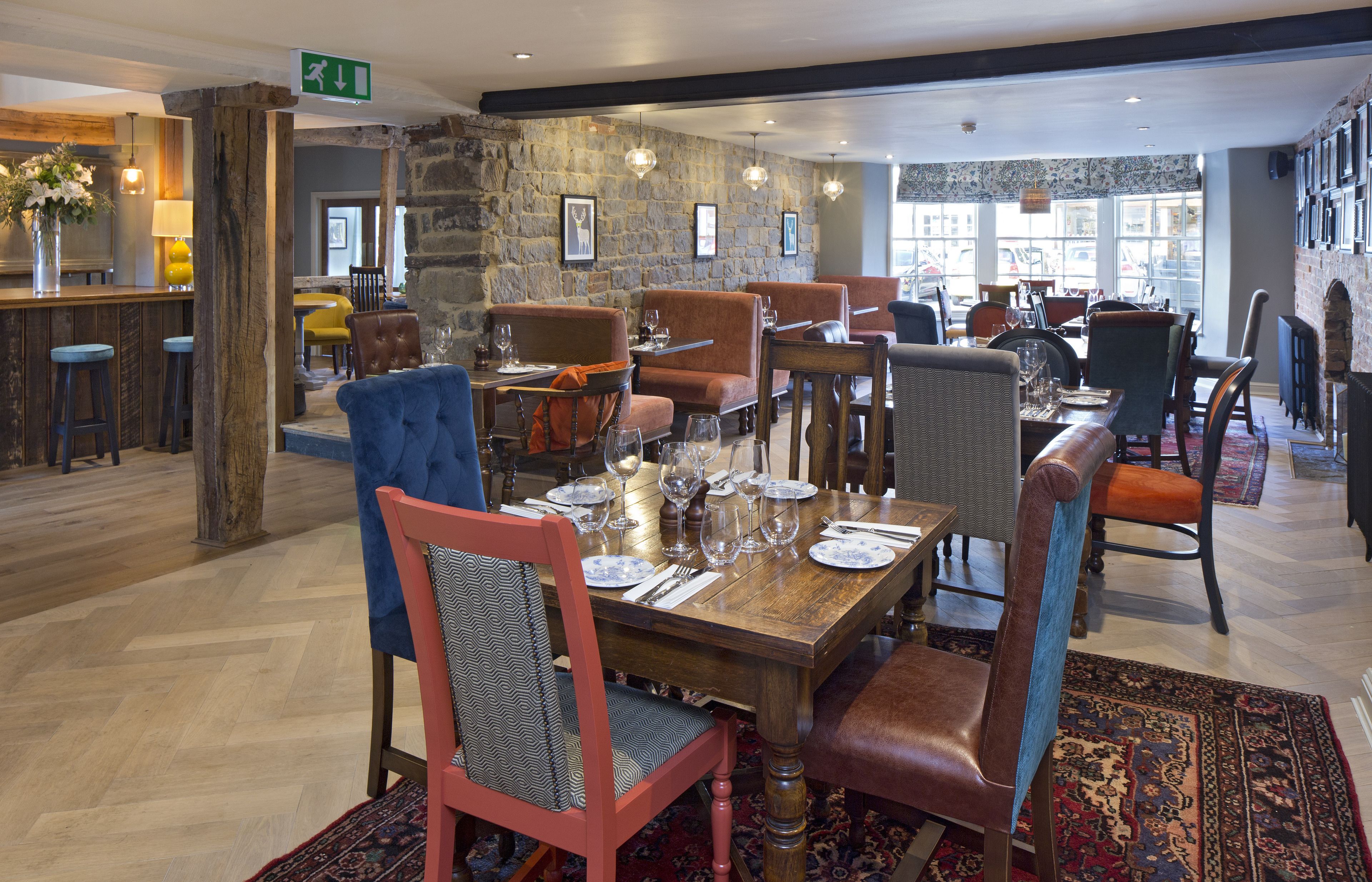A restaurant with wooden tables, leather chairs, and a stone wall.