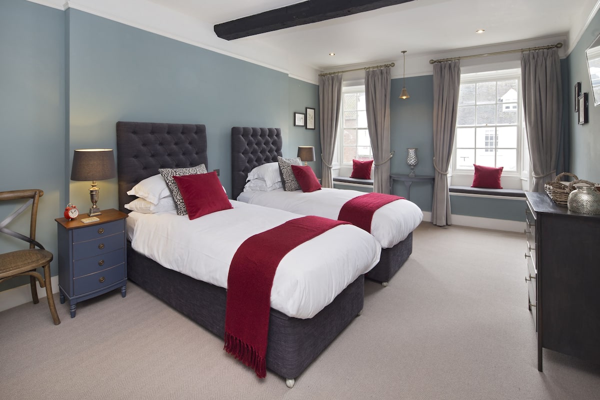 A double bed with a dark headboard, a bedside table with a lamp, and a red throw blanket.