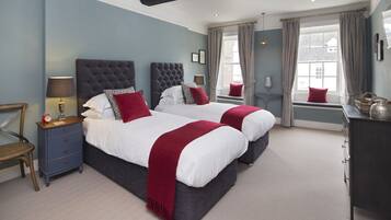 A double bed with a dark headboard, a bedside table with a lamp, and a red throw blanket.