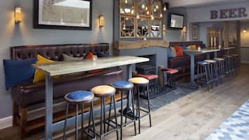 A cozy bar area with a wooden table, cushioned seating, and bar stools.