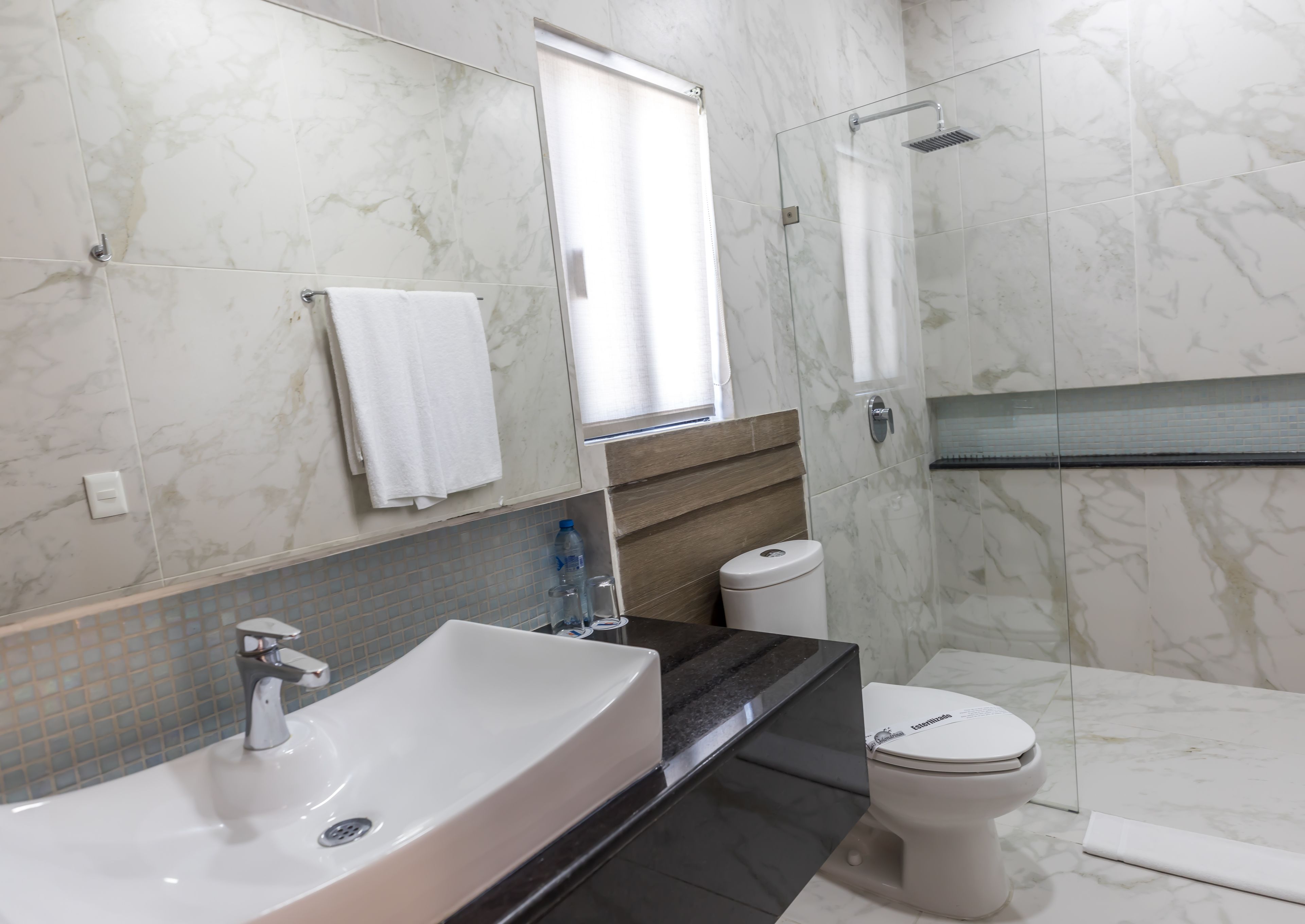 A modern bathroom with a marble sink, a toilet, and a shower.