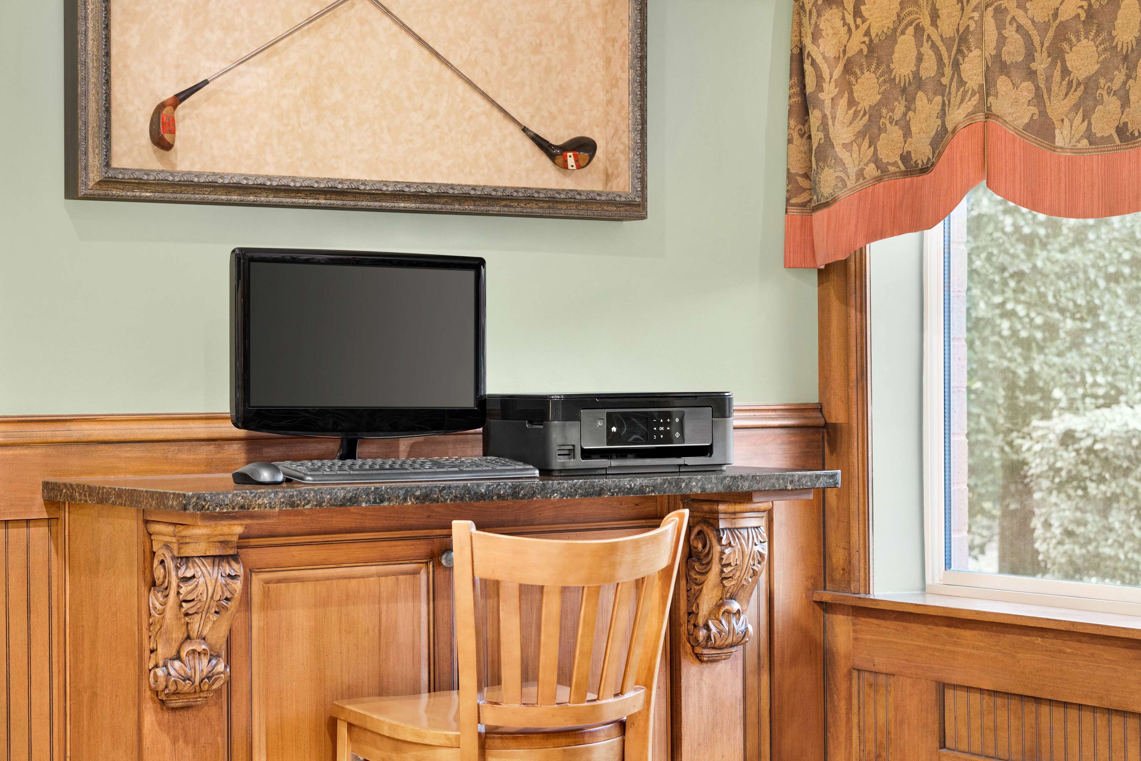 A wooden desk with a monitor, keyboard, and printer.