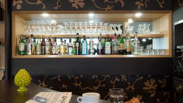 Eine Bar mit Flaschenregal, Gläsern, einer Zeitung, einer Tasse und einem Teller mit Speisen.