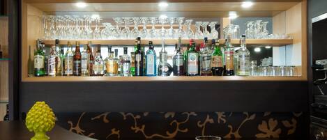 A bar area with a shelf of bottles and glasses, a newspaper, a cup, and a plate with food.