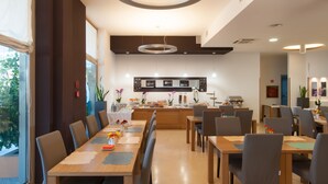 Un comedor moderno con una larga mesa de madera, varias sillas y una cocina al fondo.