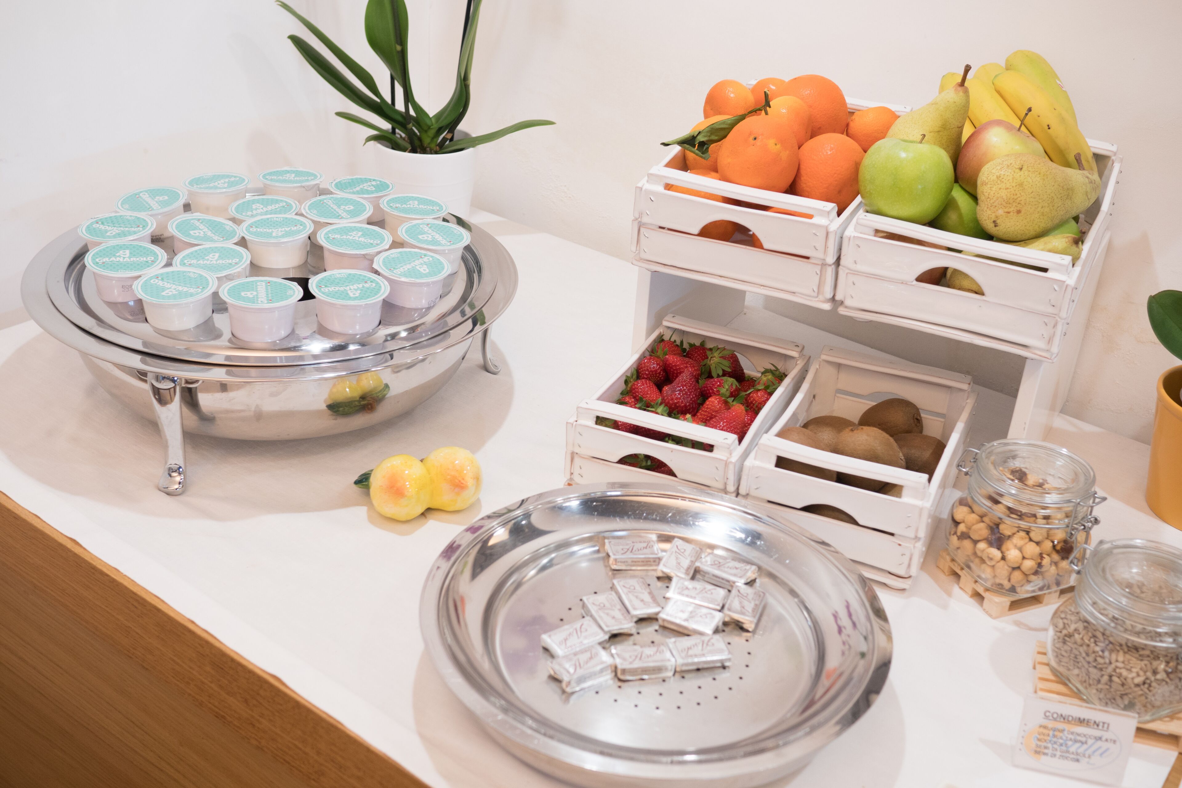 Un tavolo per buffet con diversi cibi, tra cui frutta, pasticcini e frutta secca.