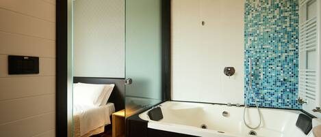 Een moderne badkamer met een douchecabine van glas, een ruim bad en een aparte douchehoek.