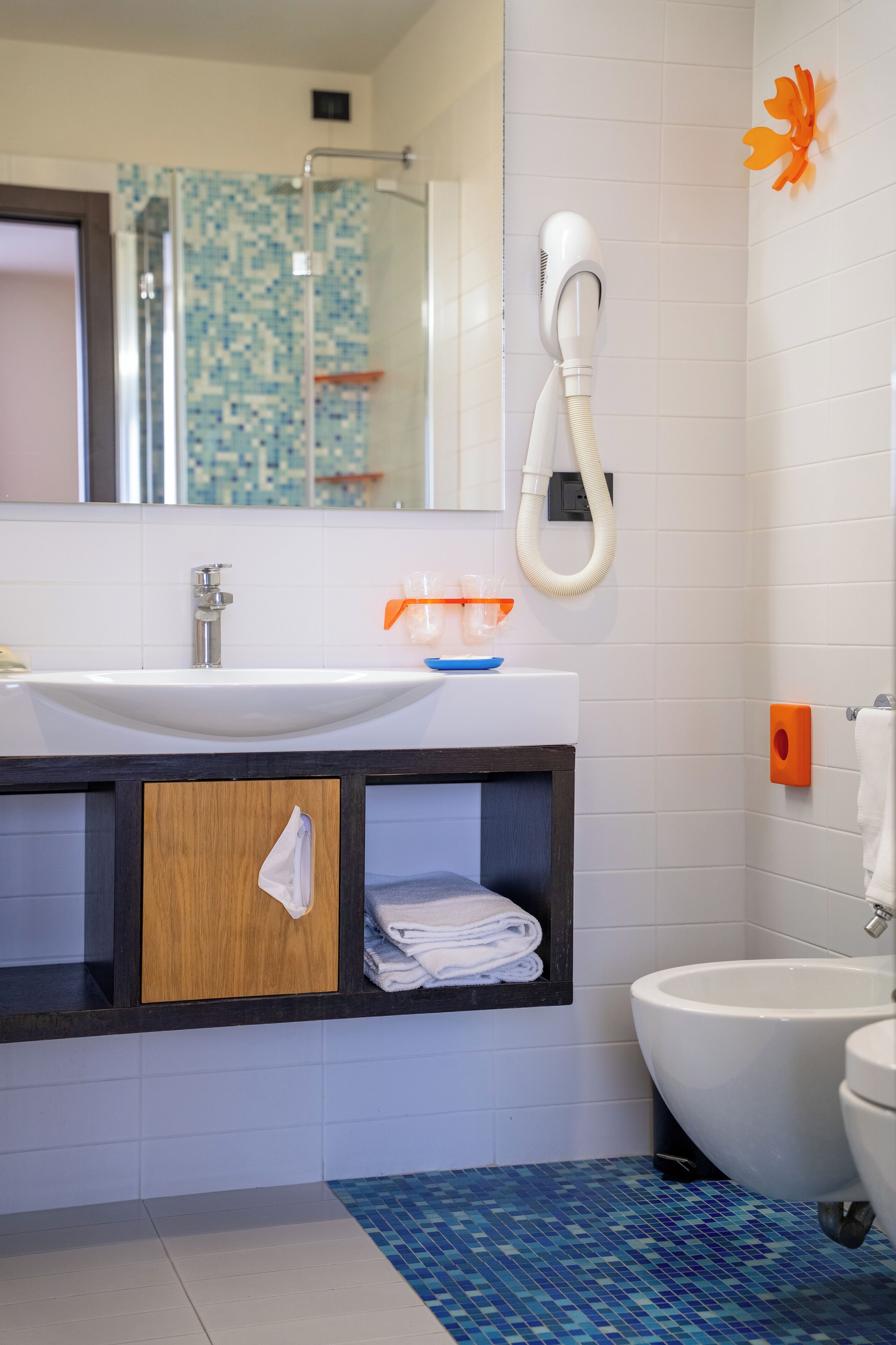 A bathroom with a white sink, a mirror, a toilet, and a shower area.