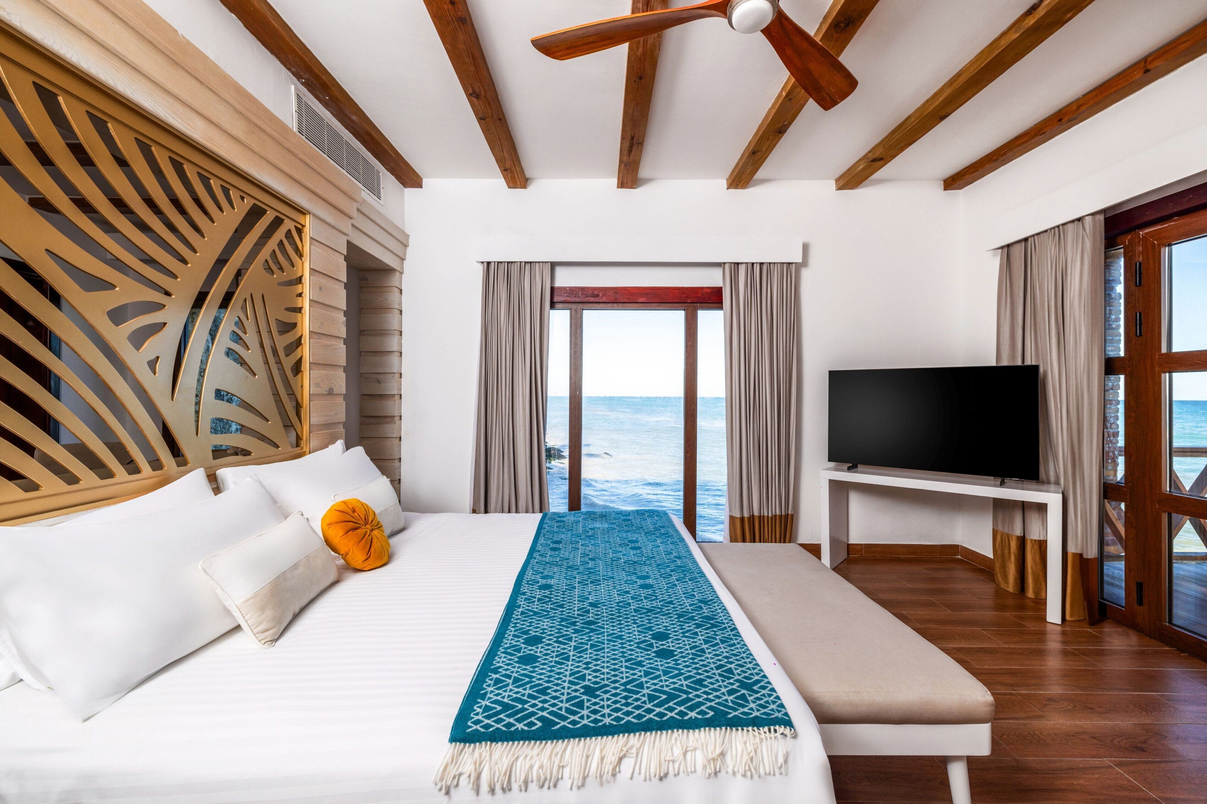 Un dormitorio con cama, televisor y vista al mar.