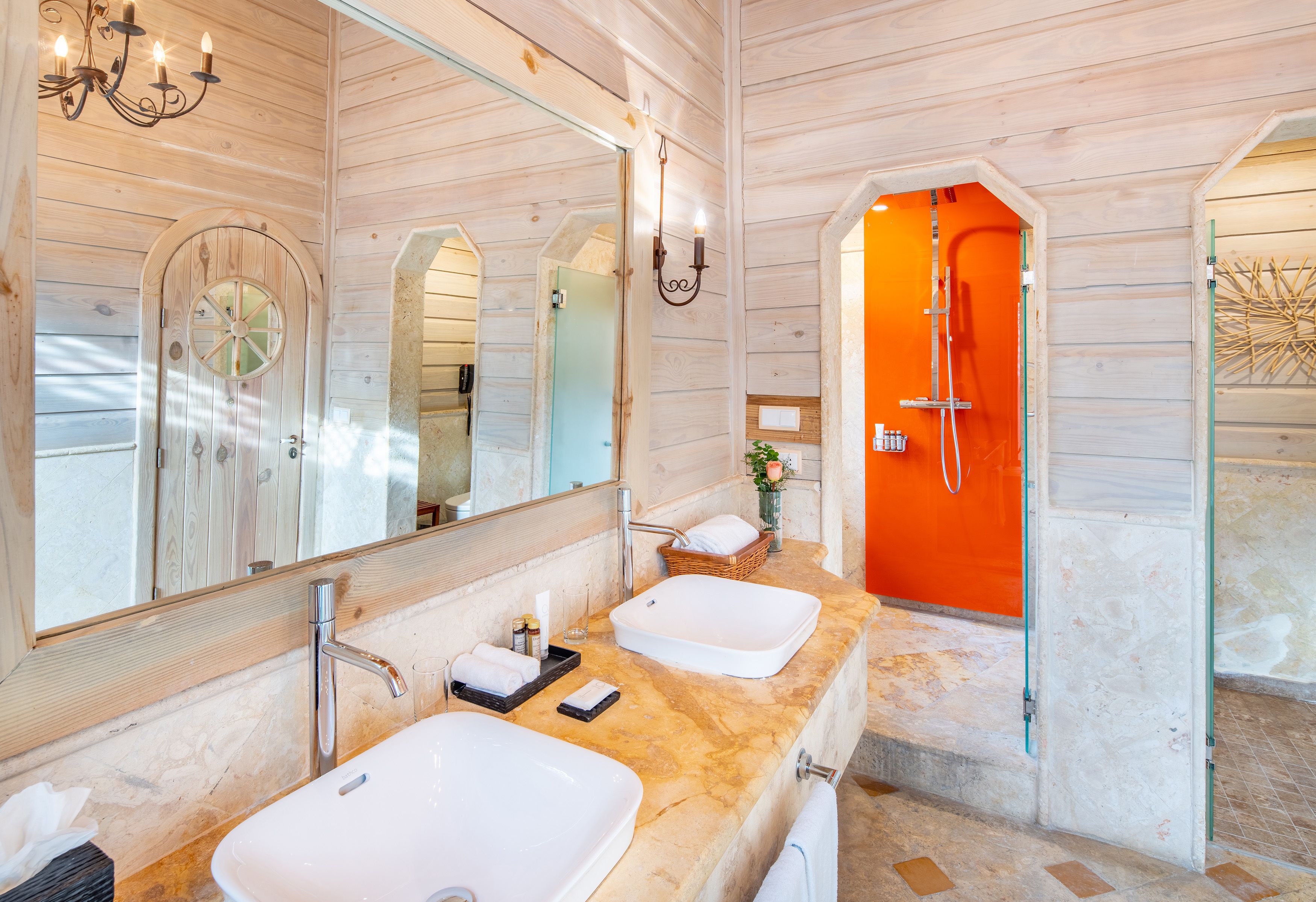 Un interior de madera con un espejo grande, dos lavamanos y una zona de ducha.
