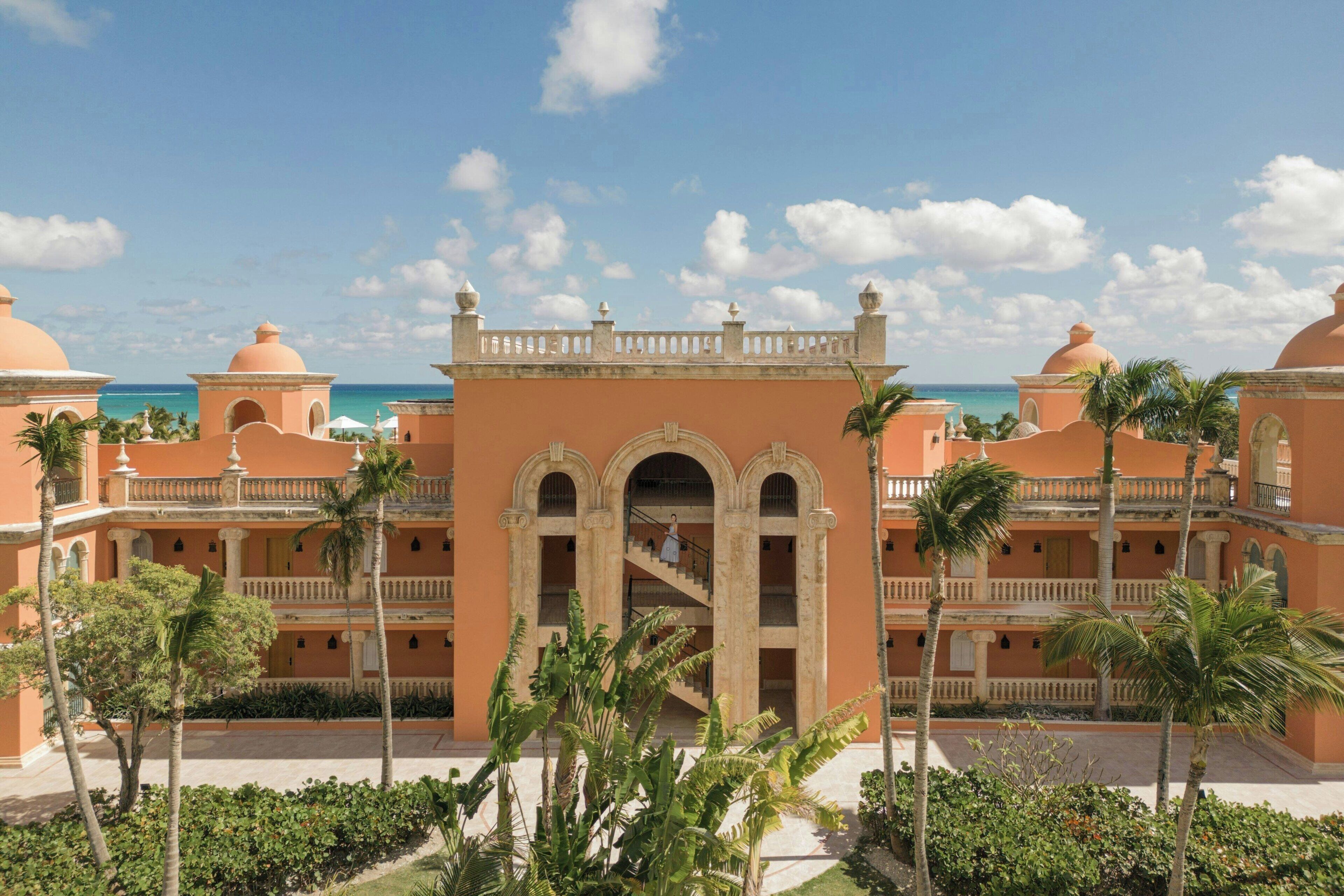 Un hotel con un patio central, palmeras y vistas al océano.