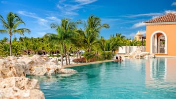 Relax by the tranquil pool surrounded by lush palm trees and natural rock formations.