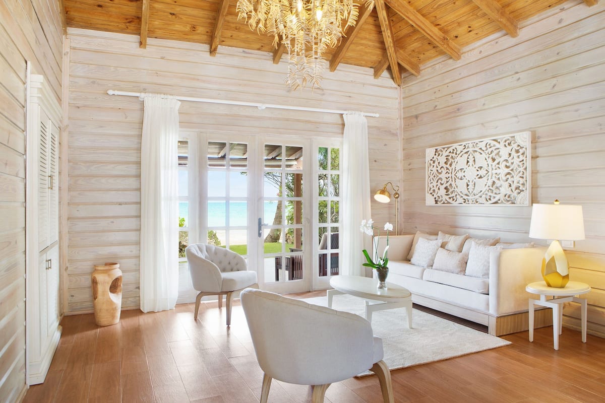 A spacious room with a wooden ceiling and large windows, a white sofa, a coffee table, and a chandelier.